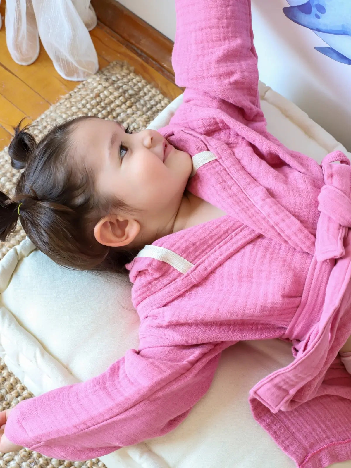 Pembe muslin bebek bornozu giyili çocuk model yatar pozisyon