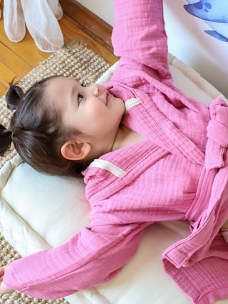 Pembe müslin bebek bornozu giyili çocuk model yatar pozisyon