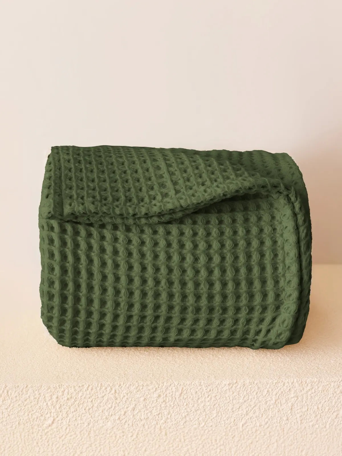 Koyu yeşil waffle pike yatak örtüsü katlanmış halde petek doku görünümü